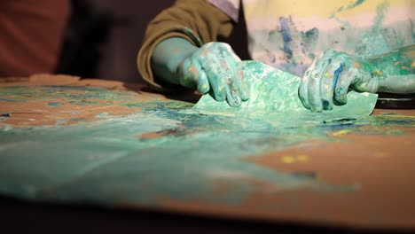 Young-boy-painting-with-his-hands-on-on-the-table