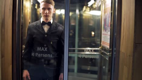 joven y exitoso hombre de negocios en un traje con una corbata mariposa llegando y saliendo del ascensor con puertas de vidrio