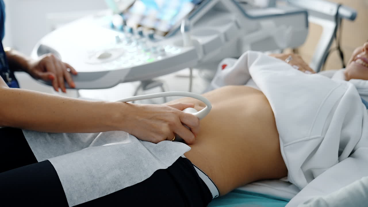 Doctor moving sensor of ultrasound machine by the female belly. Ultrasonic diagnostics on early stages of pregnancy.