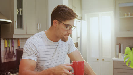 young man wearing spectacles sitting on stool having coffee while using laptop 4k 4k