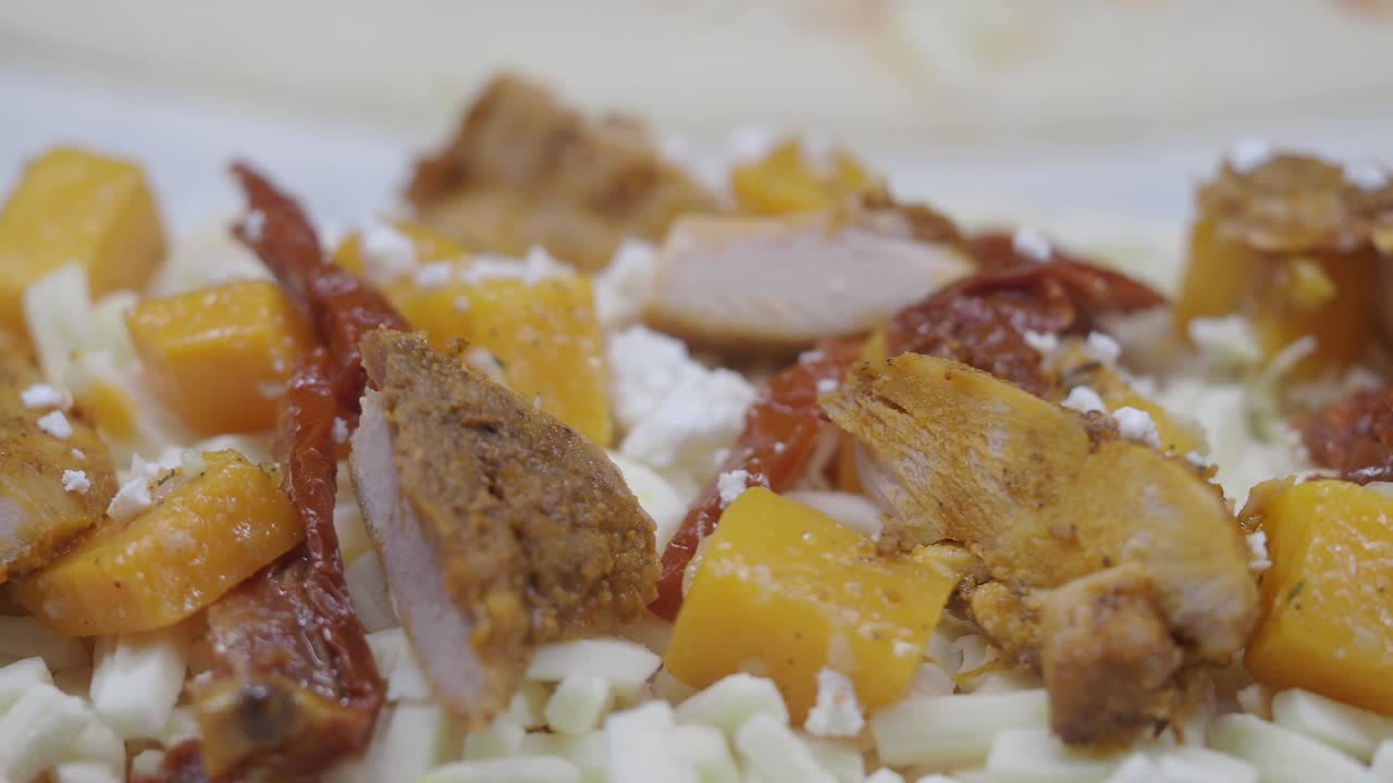 Close-up of food ingredients including chicken, cheese, and vegetables