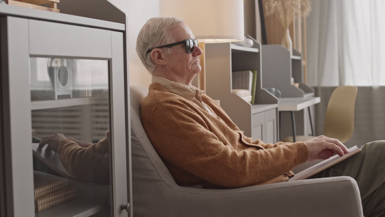 Blind Elderly Man Reading Braille Book at Home
