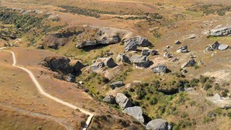 toma aérea sobre un grupo de rocas y un sendero en el área de canterbury, nueva zelanda