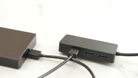 el hombre conecta el cable usb del disco duro externo al concentrador para realizar copias de seguridad y transferir datos digitales