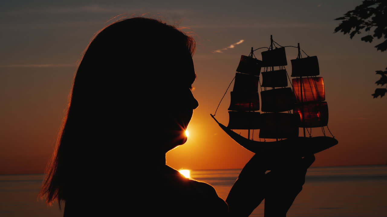 석양에 장난감 범선을 가진 여자의 프로필