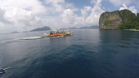 boat with tourists approaching helicopter island in el nido palawan philippines