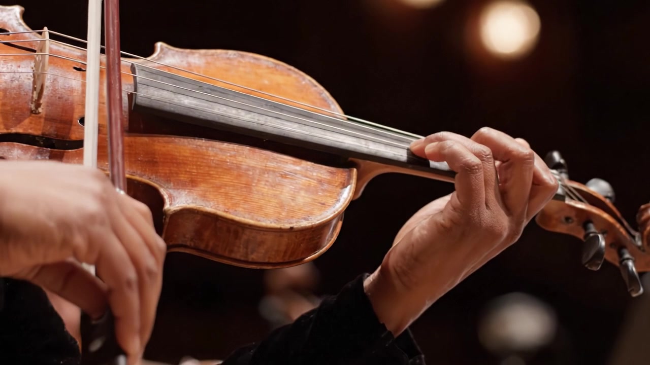 Un Primo Piano Intimo della Mano di un Violinista che Suona Magistralmente lo Strumento, Catturando la Passione e l'Arte dell'Esecuzione Musicale in un Contesto di Concerto