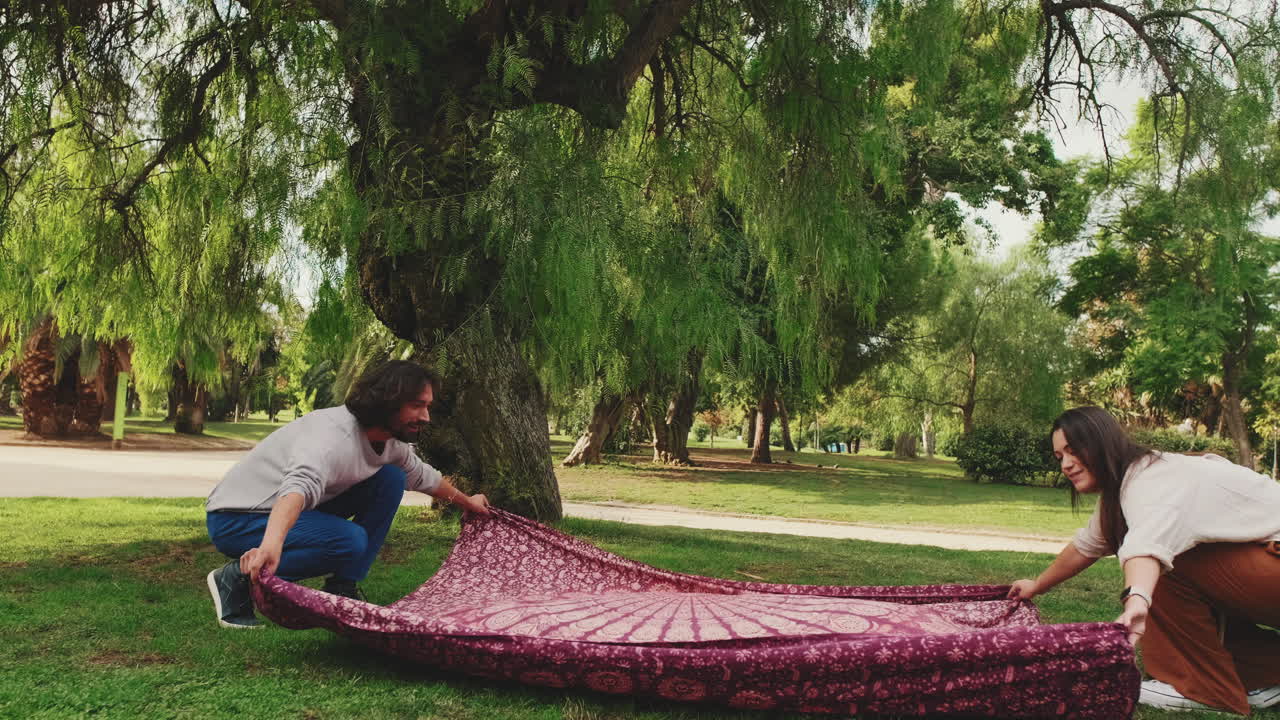 Persone che stendono una coperta da picnic in un parco