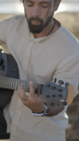 man playing acoustic guitar outdoors during golden hour