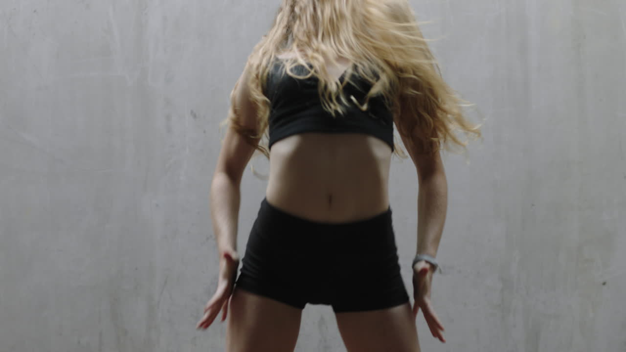 mujer bailarina hermosa joven bailarina de calle caucásica realizando movimientos contemporáneos disfrutando de la expresión de la danza moderna practicando en un almacén grungy de cerca