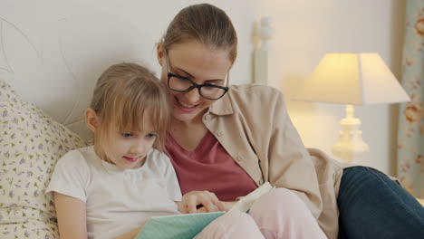 mother and daughter reading together in bedroom