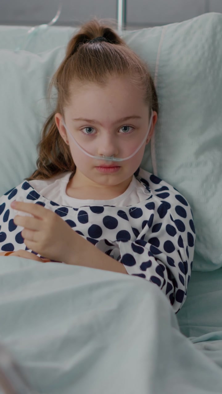 Sad Young Girl With Nasal Cannula Crying in Hospital Bed