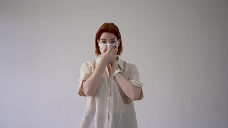 Woman-putting-on-medical-face-mask-and-looking-at-camera.-Copy-space-and-white-background.-Medium-shot,-frontal-view