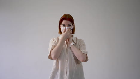 woman putting on medical face mask and looking at camera. copy space and white background. medium shot, frontal view