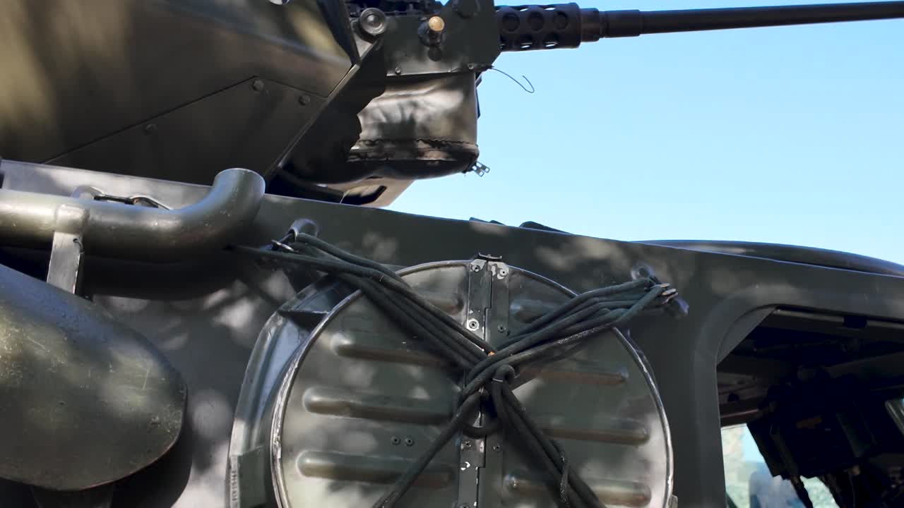 Close up of a military vehicle's interior, highlighting the open hatch, dashboard, steering wheel, and a helmet