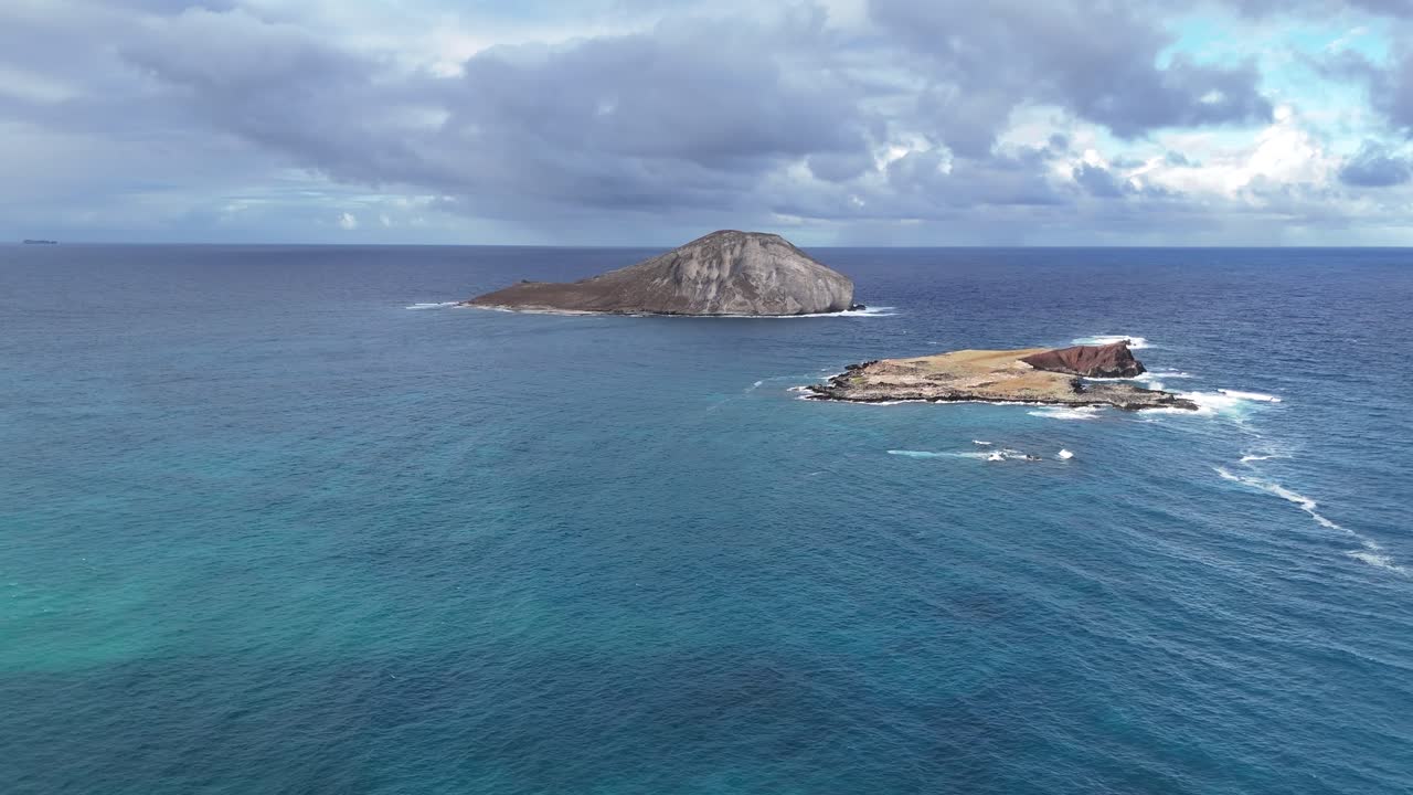 Drone aerial view near two small rocky islets off Oahu, Hawaii. Tropical ocean, dramatic coastline, and scenic island scenery captured from above