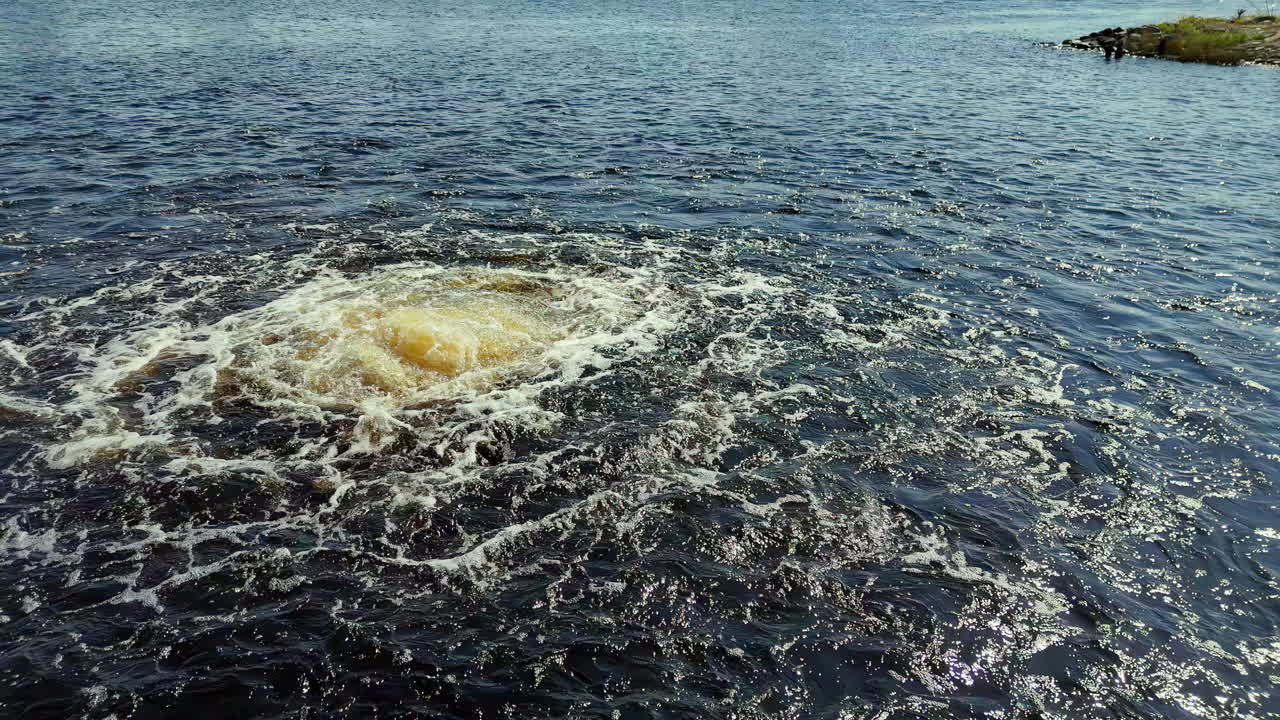Frothing Underwater Effusion of Murky, Light-Brown Liquid Breaking the Dark, Deep-Indigo Surface of the Baltic Sea on a Hazy