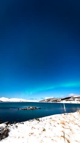 vertical view skogsfjord near rural village with aurora borealis in norway. timelapse