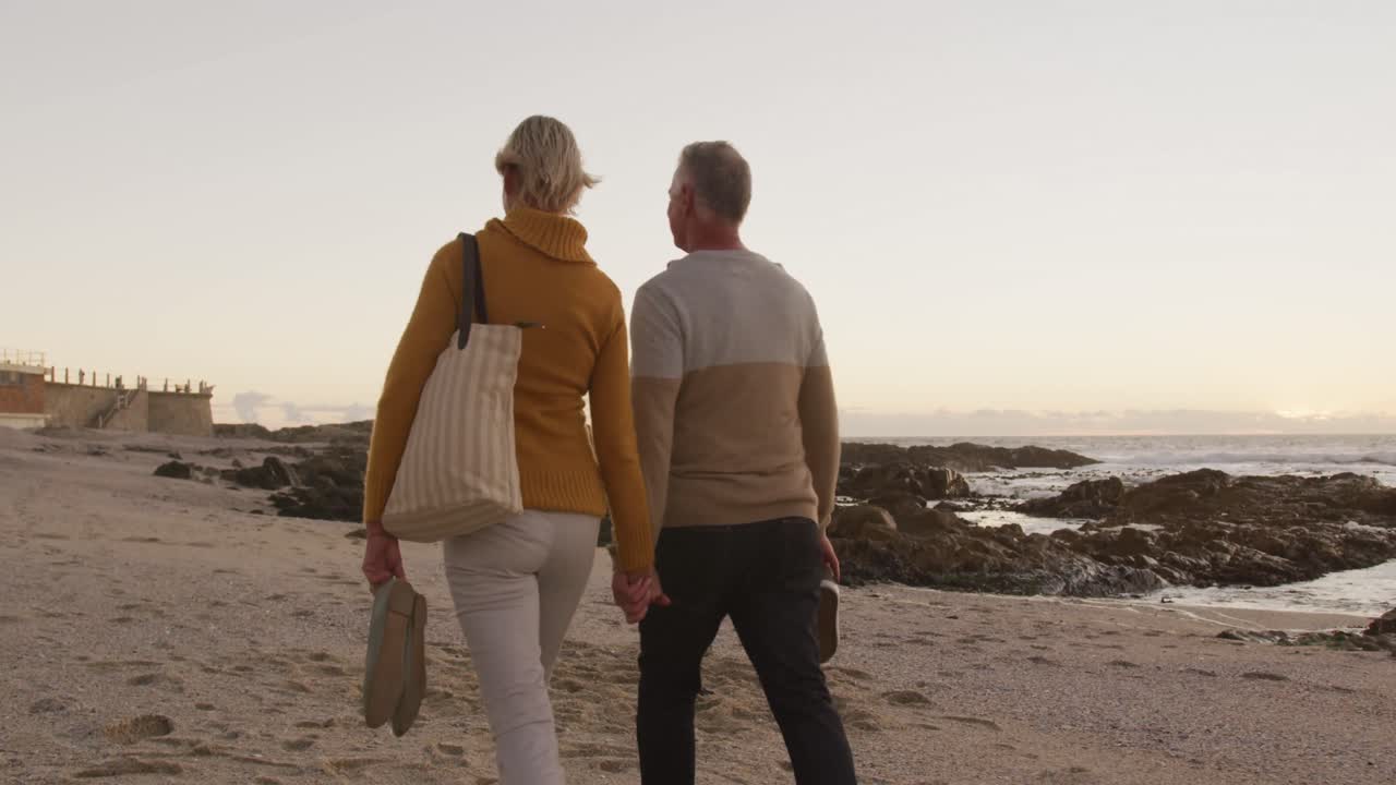 pareja de ancianos tomados de la mano en la playa