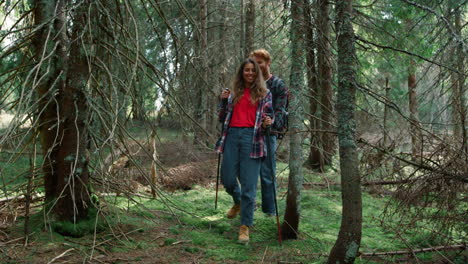 girl and guy trekking woods in summer time. smiling couple hiking in forest