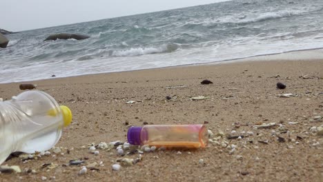 various of littered bottle trash dumped on beachfront, horizontal zoom out shot