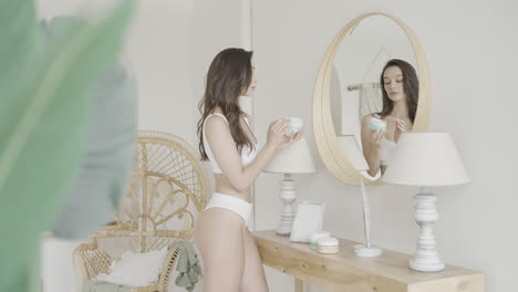 woman applying cream in front of mirror