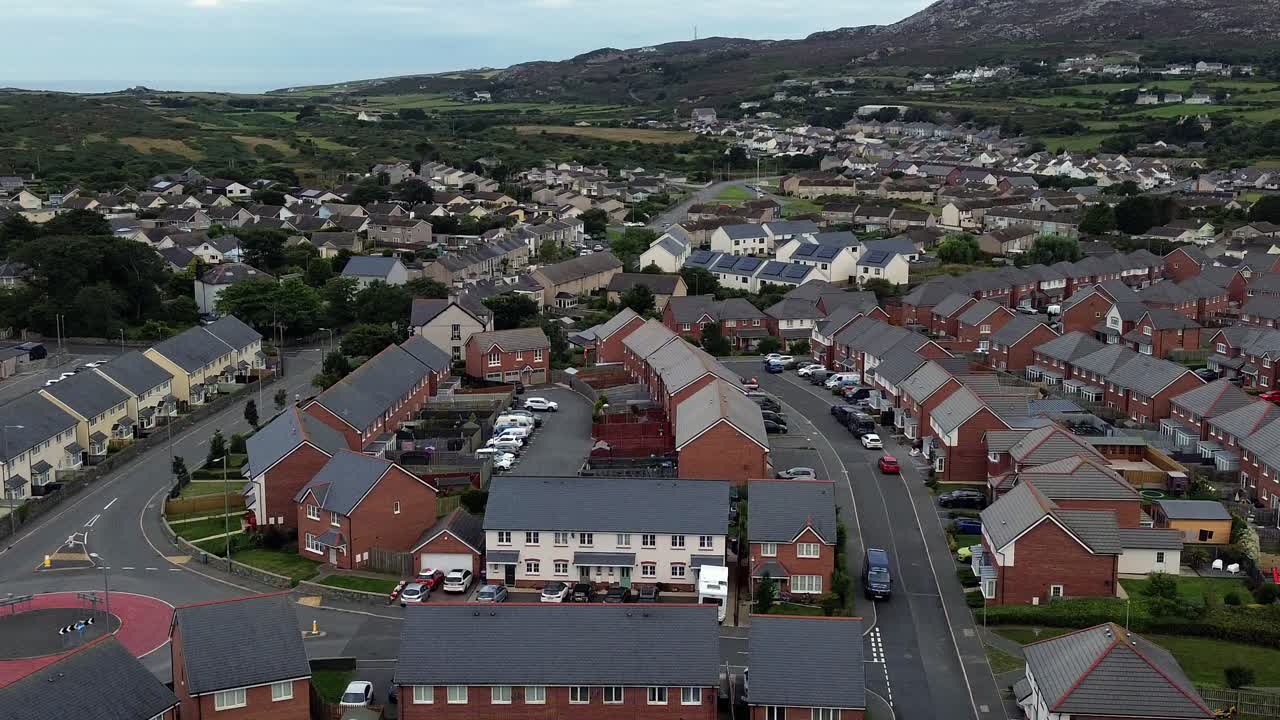 Aerial view across Welsh suburban neighbourhood community property rooftops to rocky mountain
