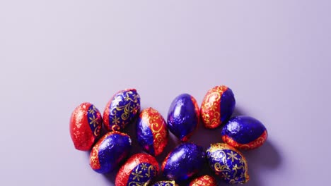 multiple chocolate easter eggs on purple background with copy space