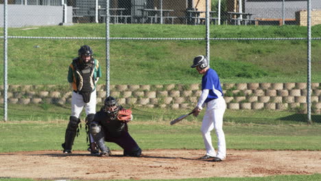 male baseball players and male umpire playing baseball, catching the ball on a pitch, slow motion