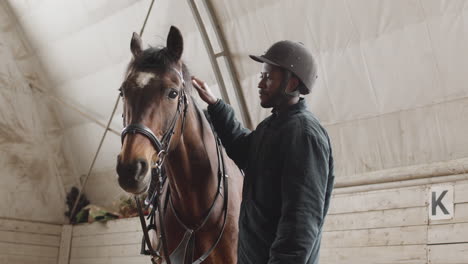 man petting a horse at a stable