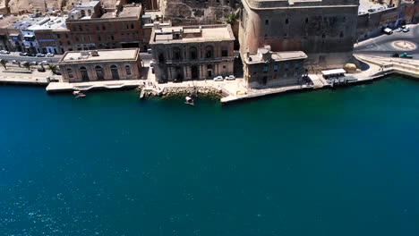 Pan-up-aerial-shot-from-over-the-azure-blue-sea-to-the-beautiful-Barrakka-Gardens-on-a-sunny-day,-Valetta,-Malta