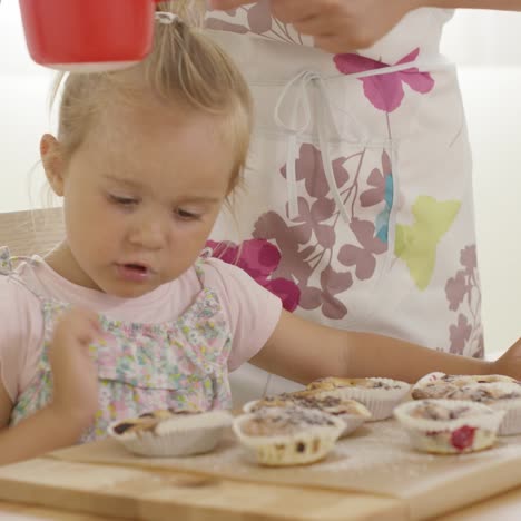 niño interesado en azúcar cayendo sobre muffins horneados