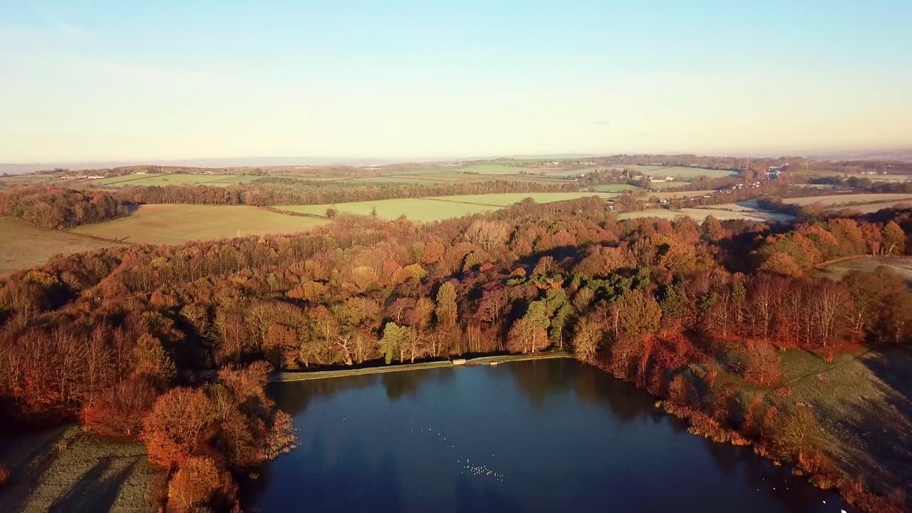 Wide Drone View Tilting Down Of Frozen Pond In Peak District National Park With Ducks And Birds Sat On The Lake In Winter At Golden Hour Sunrise