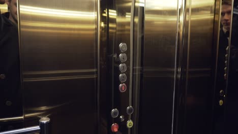 Male-hand-pushing-the-elevator-button-labeled-with-the-number-one.-Front-shot.