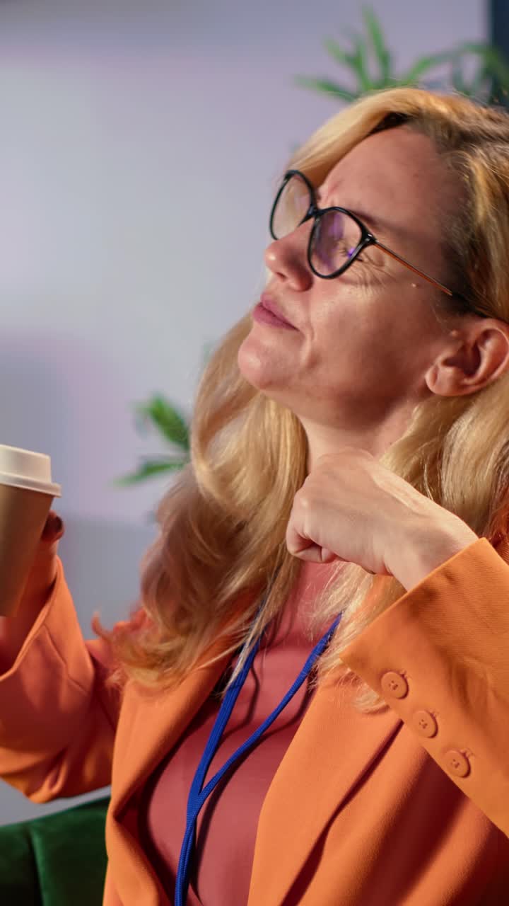 Træt forretningskvinde gaber og drikker kaffe på konference