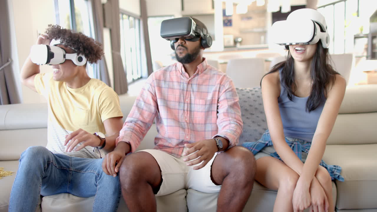 At home, Using VR headsets, diverse friends sitting on couch enjoying virtual reality gaming