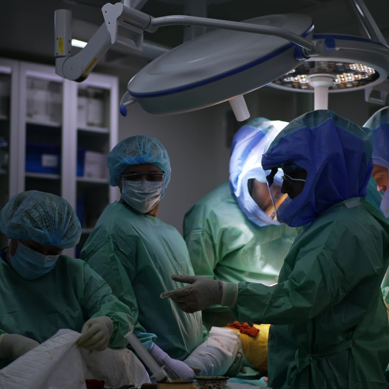 Arthroscopy performed by the team of doctors wearing protective suits and helmets. Surgeon waiting for the nurse to pass the necessary instrument