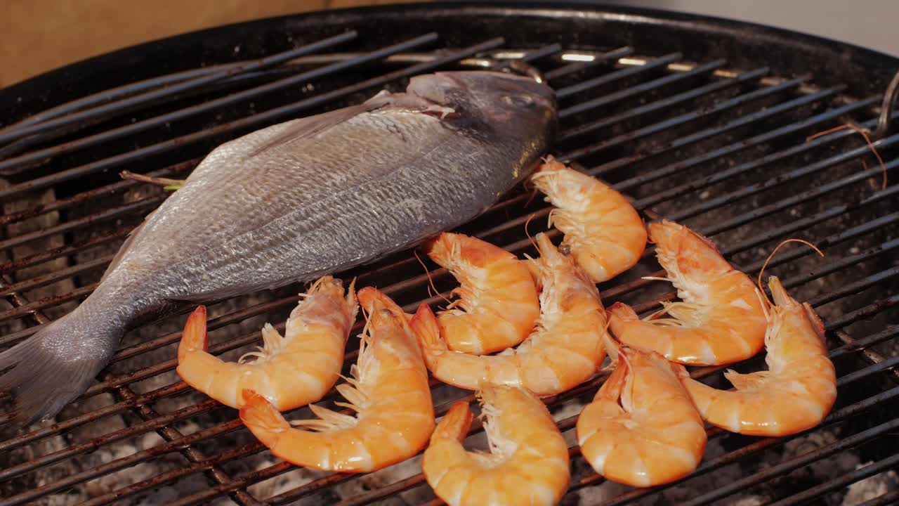 Chef cooking shrimps with oil and spices on grill close-up. Prawns on fire throwing them on pan. Dorado and salmon fish steak on frying grill. Restaurant Food concept. Sea food barbecue.