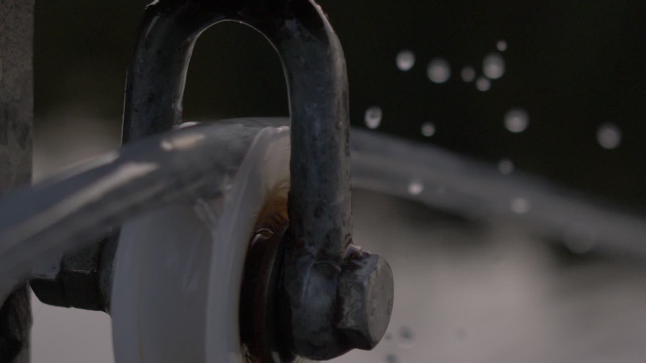 cierre el mecanismo borroso de una rueca giratoria con gotas de agua en cámara lenta cayendo