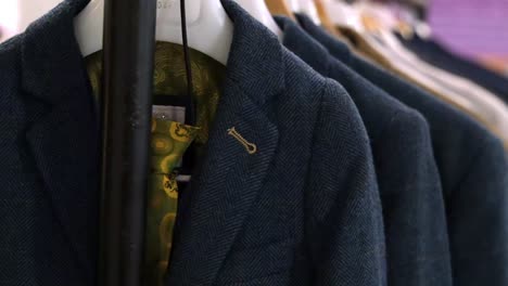 elegant display of different coloured wedding suits by designer collection. trendy male fashion essentials on hangers.