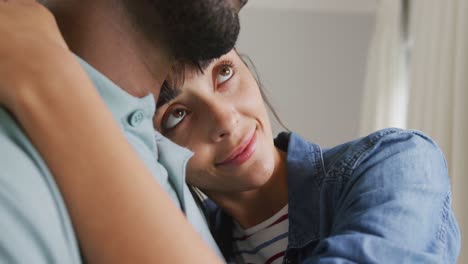 happy diverse couple wearing jacket and shirt and embracing in living room