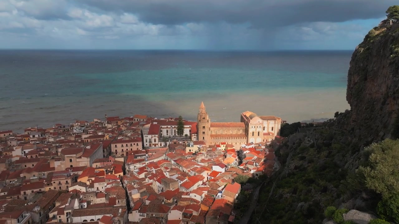 Veduta aerea che sorvola la scogliera di Cefalù, i tetti e la chiesa vicino al mare