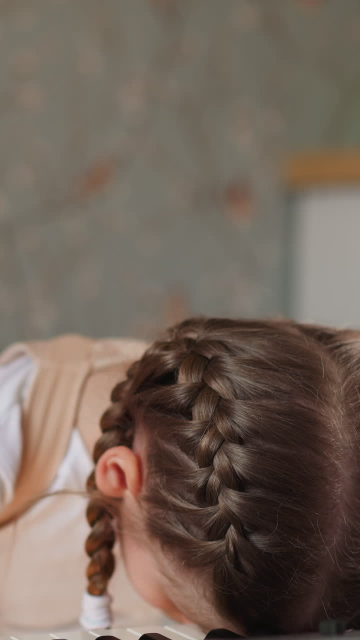Weary girl pianist rolls eyes and exhales heavily. Fatigued child rests head on synthesizer keyboard feeling bored closeup on blurred background