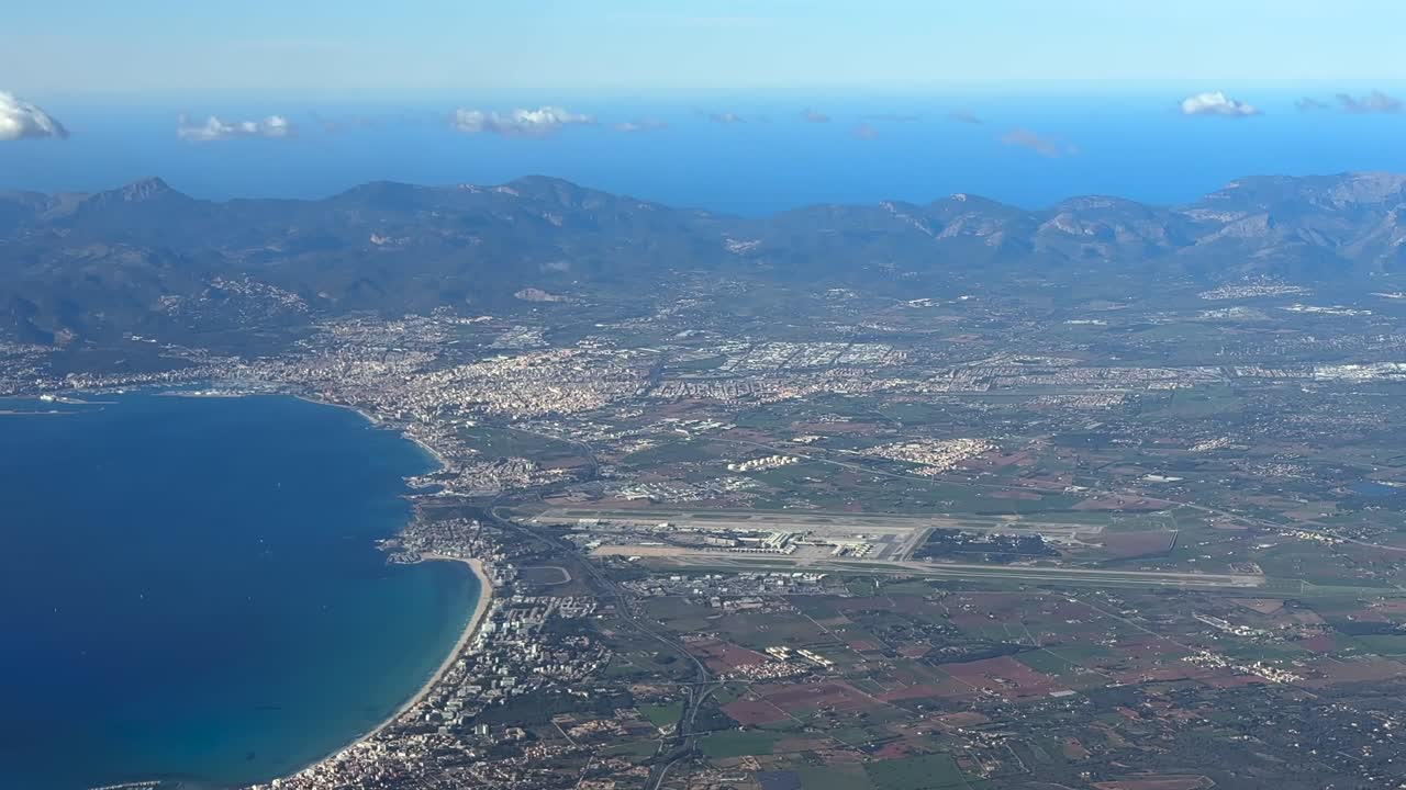 An elevated aerial side spinning view of Palma de Mallorca city, airport and bay taken from an airplane cockpit