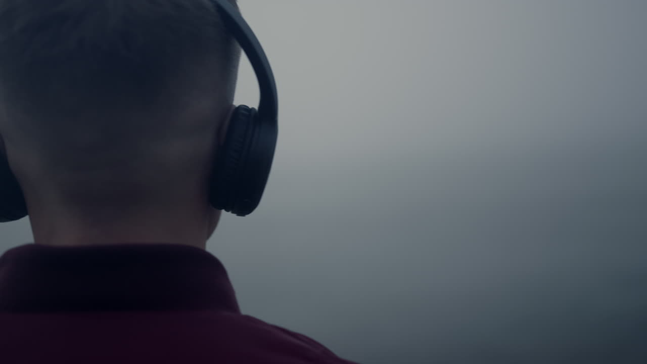 ビーチでヘッドホンをして音楽を聴く男性。イヤホンで音楽の曲を楽しむ男性