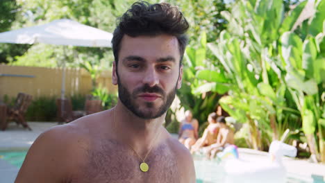 portrait of bare chested hispanic man outdoors with friends enjoying summer pool party