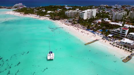 luxury boat anchored in blue water off resort island playa norte, isla mujeres mexico, 4k drone flyover