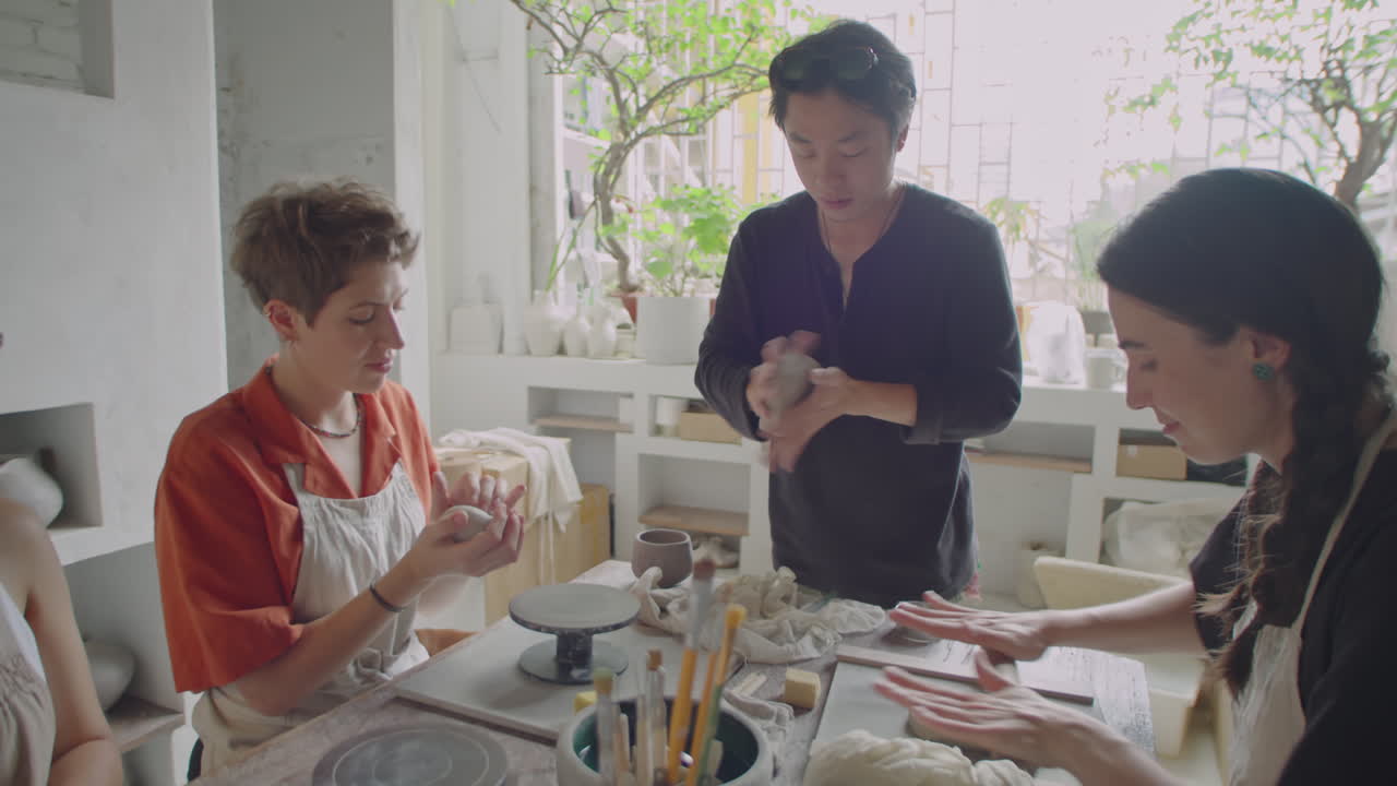 Asian Potter Teaching Students How to Work with Clay