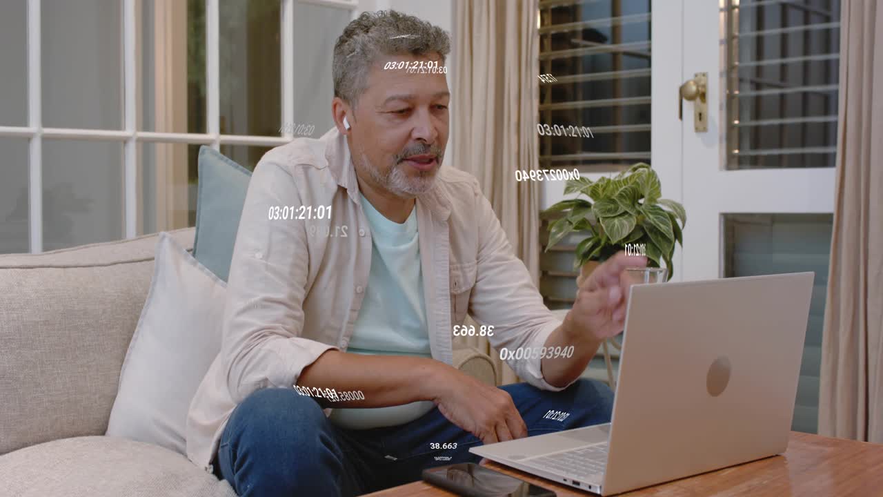 Man on couch joining remote call on laptop, speaking, typing while hex overlays floating over him