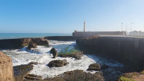 las olas chocan contra las rocas, salpican sobre el acantilado, el faro de rabat en la orilla del océano atlántico